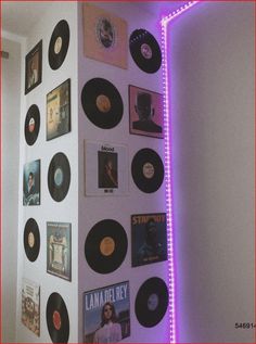 a wall with various records on it and purple light coming from the bottom right corner