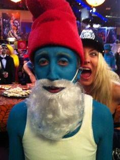 a man with blue paint on his face and white beard wearing a red santa hat