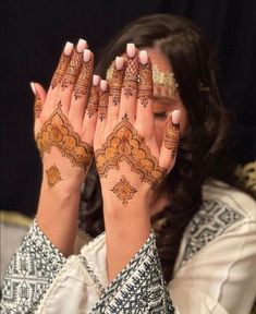 a woman with henna on her hands and hand covering it's face while she looks at the camera