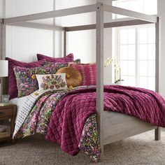 a bed with purple comforter and pillows on it