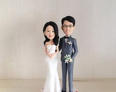 a bride and groom cake topper are posed for a photo on their wedding day