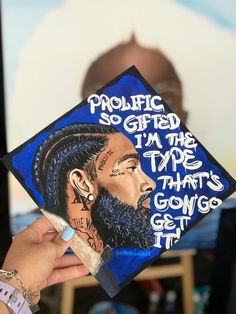 a person holding up a graduation cap with the image of a man's face on it