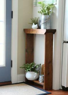 a wooden shelf with potted plants on top of it next to a blue door