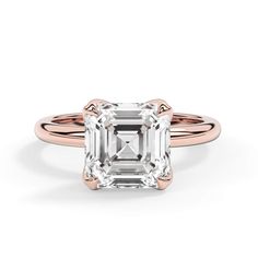 an emerald - cut diamond engagement ring in rose gold with two clawed shans