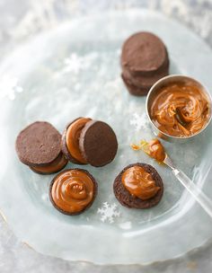 chocolate cookies and peanut butter on a glass plate with a spoon next to them, ready to be eaten