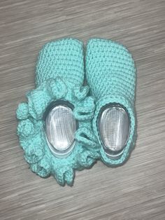 a pair of blue knitted baby shoes with silver metal eyeballs on the soles