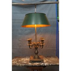 a green lamp sitting on top of a wooden table next to a blue sheet covered wall