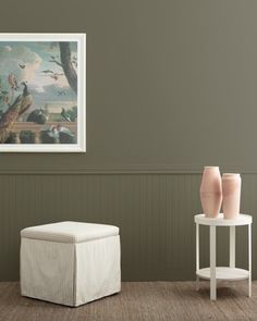 two vases sitting on top of a table next to a white stool and ottoman