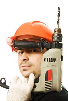 a man wearing a hard hat and holding a driller on his head with one hand