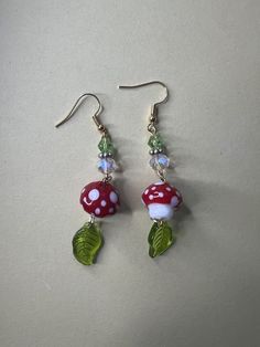 a pair of earrings with red and white mushrooms on them