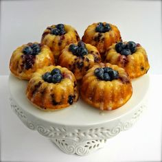 small blueberry bundts on a white cake plate with fresh blueberries in the middle