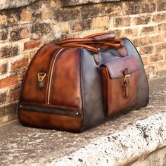 Ideal for overnight or weekend trips, the travel duffle is the best option to carry all your essentials in style. There’s virtually no place where a leather duffel bag would feel awkward or out of place. It measures 21.6 x 11.8 x 11.0 inches / 55 x 30 x 28 cm and features an outside pocket perfect for the little items that could otherwise get lost at the bottom of your bag, full lined interior and a removable shoulder strap. THE DETAILS: Materials: grey painted calf + med brown painted calf + da Leather Travel Bag For Weekend Trips, Luxury Leather Shoulder Bag For Weekend Trips, Luxury Leather Satchel For Weekend Trips, Luxury Shoulder Bag For Weekend Trips With Leather Lining, Luxury Leather Briefcase For Trip, Luxury Travel Luggage With Leather Backing, Luxury Brown Duffle Bag For Business Trips, Luxury Bags With Leather Backing For Weekend Trips, Luxury Leather Travel Bag For Trips