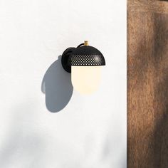 a black and white light on the side of a wall next to a wooden door