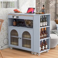 a laptop computer sitting on top of a blue cabinet filled with bottles and wine glasses