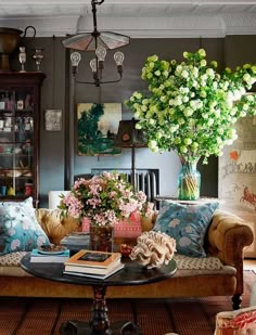 a living room filled with lots of furniture and flowers on top of a coffee table