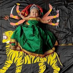 a baby in a green dress laying on top of a tiger