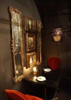 a dining room table with red chairs and two framed pictures on the wall above it