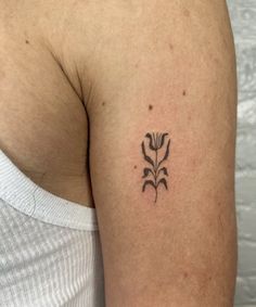 a woman's arm with a small flower tattoo on the back of her shoulder