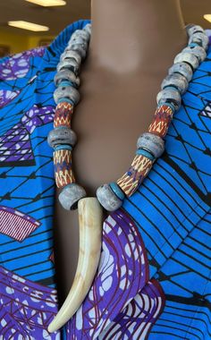 This Tribal necklace makes with indigo imported beads from Gambia. A true stand out and amazing. Piece . This precious necklace is s4 inches in length.  long. This necklace would look great on solid color garments.The color of the handmade jewelry make you calm and reminds of the calm sounds of the ocean. The horn pendant is a replica horn. Don't delay order yours today, Traditional Wooden Beaded Necklaces, Artisan Fair Trade Beaded Necklace For Festivals, Traditional Wooden Beaded Necklaces For Festivals, Traditional Blue Wooden Beaded Necklaces, Traditional Fair Trade Beaded Necklaces With Round Beads, Traditional Blue Wooden Beads, Artisan Wooden Beads For Festivals, Traditional Wooden Beaded Necklaces With Round Beads, Traditional Beaded Necklace With Wooden Round Beads