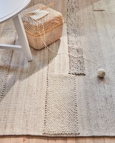 the rug is on the floor next to a table and chair with a basket in front of it