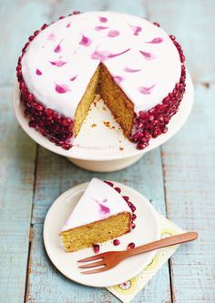 there is a cake with white frosting and red berries on the top, next to a fork