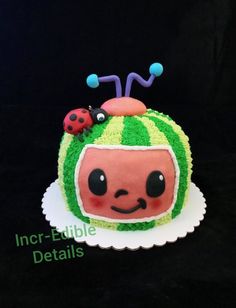 a cake decorated to look like a watermelon with ladybugs on top