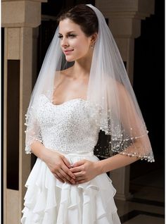 a woman in a wedding dress with a veil on her head and one arm around her waist