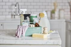 cleaning supplies are sitting on the counter top in this kitchen sink area, including soap, sponges, and other household care products