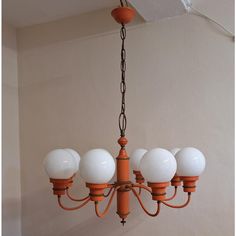 an orange chandelier with five white globes hanging from it's ceiling