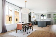 a large open kitchen and dining room with hardwood floors, white walls, and wood flooring