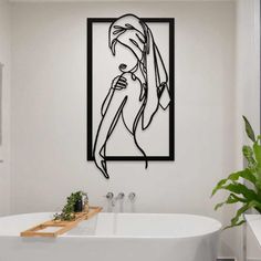 a white bath tub sitting under a black framed artwork on the wall next to a potted plant