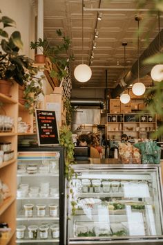 the inside of a bakery with plants growing on the counter and shelves full of food