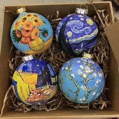 four painted christmas ornaments in a cardboard box