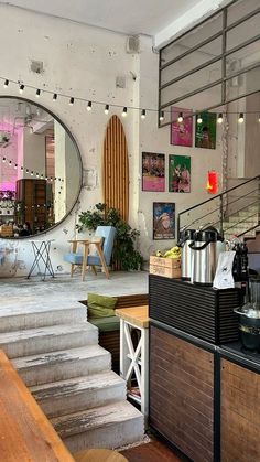 the inside of a coffee shop with stairs leading up to an open door and tables in front of it