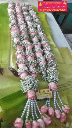 pink flowers are arranged in rows on a banana leaf table with other items around it