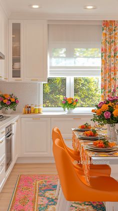 a kitchen with white cabinets and an orange dining table surrounded by bright colored chairs in front of the window