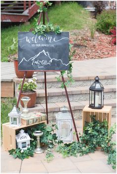 a welcome sign is set up on the steps with greenery and lanterns around it