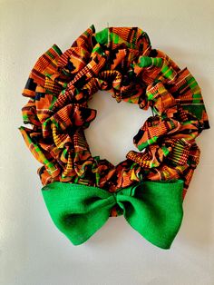 an orange and green scarf tied to a white wall with a green bow on it