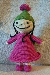 a crocheted doll with a pink dress and green hat on it's head