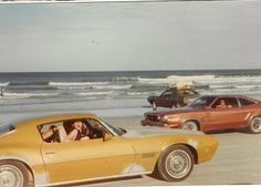 two cars parked on the beach next to each other with people in the back seat