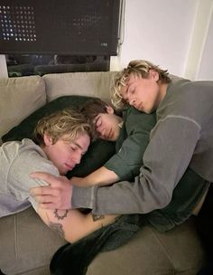 two young men are sleeping on a couch with their arms around each other as they hug