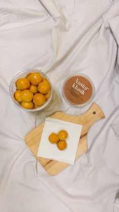 some oranges are sitting on a bed next to a bowl of yogurt