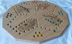 a wooden board game with lots of different colored dots and flowers on the top, sitting on a white sheet