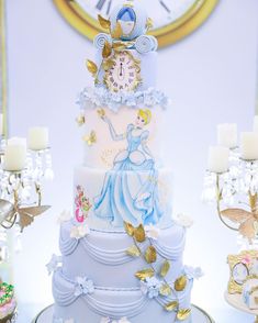 a three tiered cake decorated with blue and white frosting, surrounded by candles