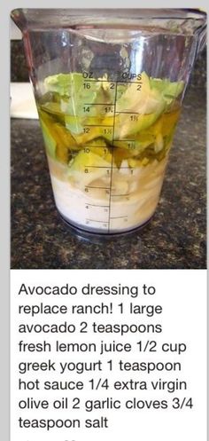 a blender filled with green liquid on top of a counter next to a measuring cup