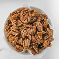 a white bowl filled with pecans on top of a table