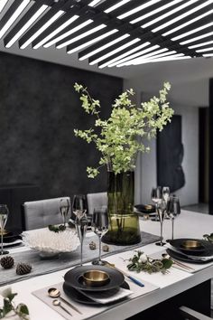 a dining room table with place settings and flowers in a vase on the centerpiece