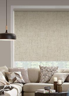 a living room filled with furniture and a large window covered in roman blind shades on the windowsill