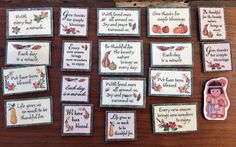 cross stitch cards and magnets on a wooden table with words written in small squares