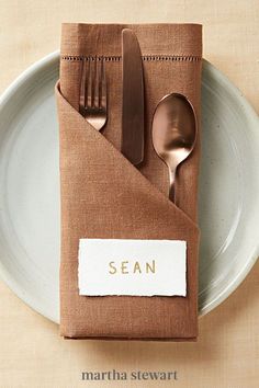 a place setting with spoons, fork and knife on a plate that has the word sean written on it